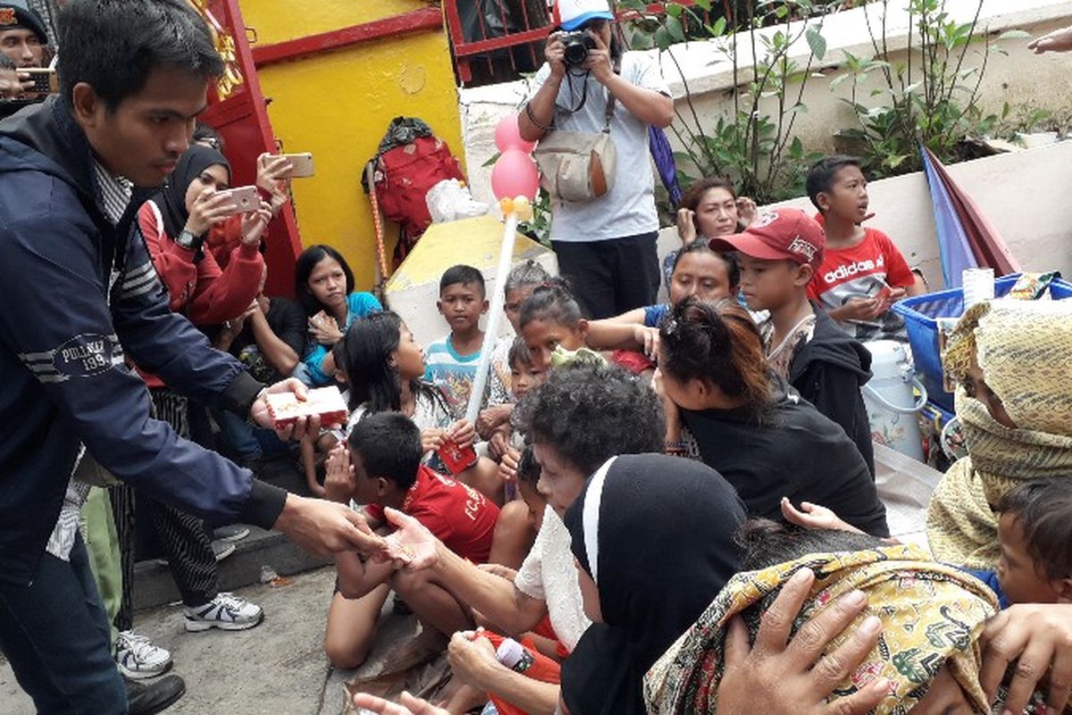 Seorang pria membawa 500 lembar angpao untuk dibagikan ke orang-orang yang menunggu di halaman area Vihara Dharma Bhakti, Pecinan Petak Sembilan, Glodok, Jakarta Barat pada Jumat (16/2/2018).
