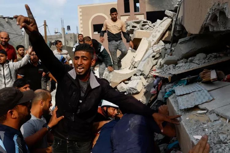 Warga Palestina mencari korban di antara puing-puing rumah yang hancur akibat serangan balik Israel di Khan Younis, di Jalur Gaza selatan pada Minggu (8/10/2023).