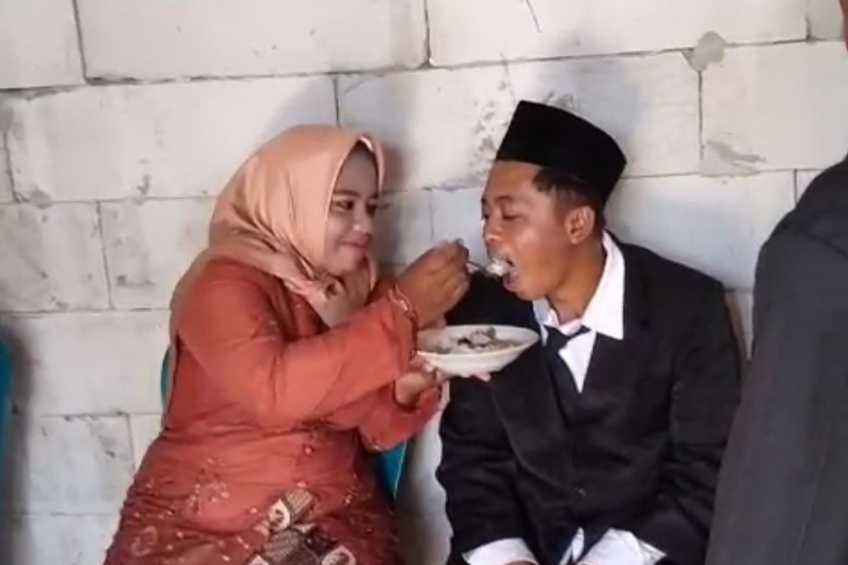SUAPI—Mempelai perempuan, Siti Fatonah menyuapi nasi soto kepada mempelai pria Ribut Ariyanto dalam rangkaian resepsi pernikahan yang berlangsung sederhana di Kelurahan Sumberejo, Kecamatan Sine, Kabupaten Ngawi, Jawa Timur. Video pernikahan keduanya viral di media sosial setelah diunggah akun Hardy@shop di Tiktok