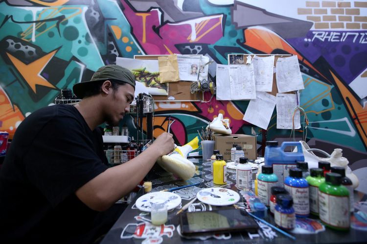 Seniman Never Too Lavish menyelesaikan proses melukis sepatu di studio Never Too Lavish, Jakarta, Selasa (10/4/2018). Belakangan nama Never Too Lavish mencuri perhatian setelah karyanya di jaket denim digunakan Presiden Joko Widodo saat turing dengan sepeda motor di Sukabumi.