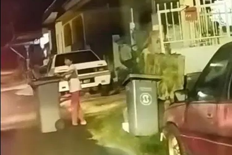 Seorang gadis cilik memindahkan tong sampah ke pinggir jalan agar mobil bisa lewat. Seorang warga sengaja menaruh tong sampah di tengah jalan untuk menutup jalan, karena kesal banyak mobil lewat di depan rumahnya di Taman Datin Fatimah, negara bagian Melaka, Malaysia.