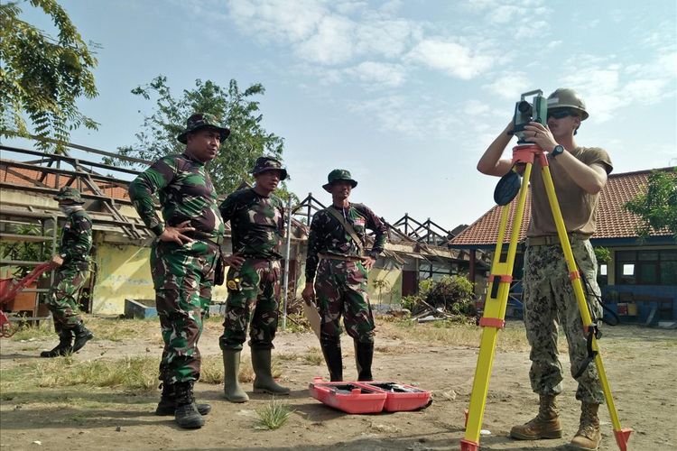 Salah seorang anggota US Navy (kanan) bersama anggota TNI, saat terlibat dalam pembangunan gedung di SDN Duduksampean, Gresik.