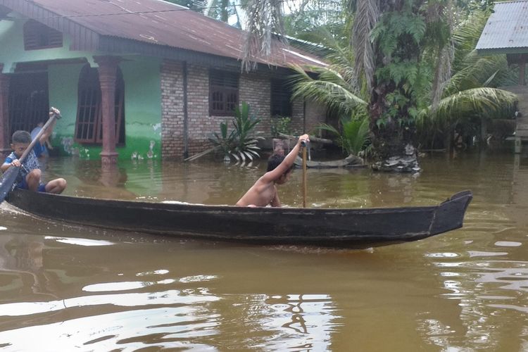 Dua orang anak sedang mendayung sampan untuk beraktivitas di tengah banjir di Desa Buluh Cina, Kecamatan Siak Hulu, Kabupaten Kampar, Riau, Jumat (20/12/2019).