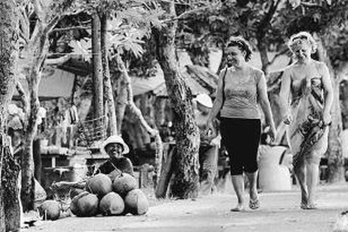 Dua wisatawan mancanegara (wisman) melintasi kawasan Pantai Nusa Dua, Bali, Minggu (25/4/2010). Krisis politik di Thailand memberikan dampak positif bagi kepariwi- sataan Bali. Jumlah wisman yang berkunjung terus meningkat belakangan ini.