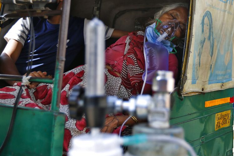 Seorang pasien Covid-19 bernapas dengan bantuan masker oksigen dan menunggu di dalam becak mobil untuk dirawat di rumah sakit pemerintah khusus Covid-19 di Ahmedabad, India.