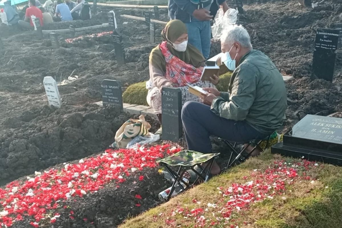 Dua orang peziarah yang sedang membacakan doa di salah satu makam di Tempat Pemakaman Umum (TPU) Selapajang, Neglasari, Kota Tangerang, Minggu (11/4/2021)