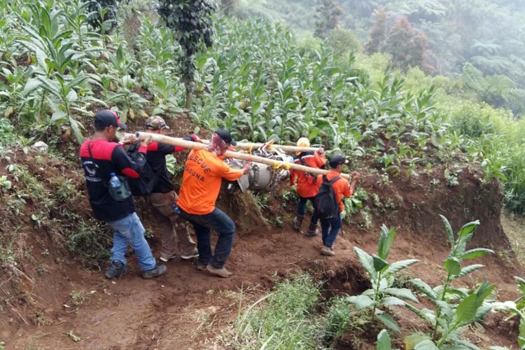 Petugas membawa serpihan bangkai helikopter Basarnas dengan bantuan bambu di lereng bukit Butak, Desa Canggal, Kecamatan Candiroto, Kabupaten Temanggung, Rabu (5/7/2017).