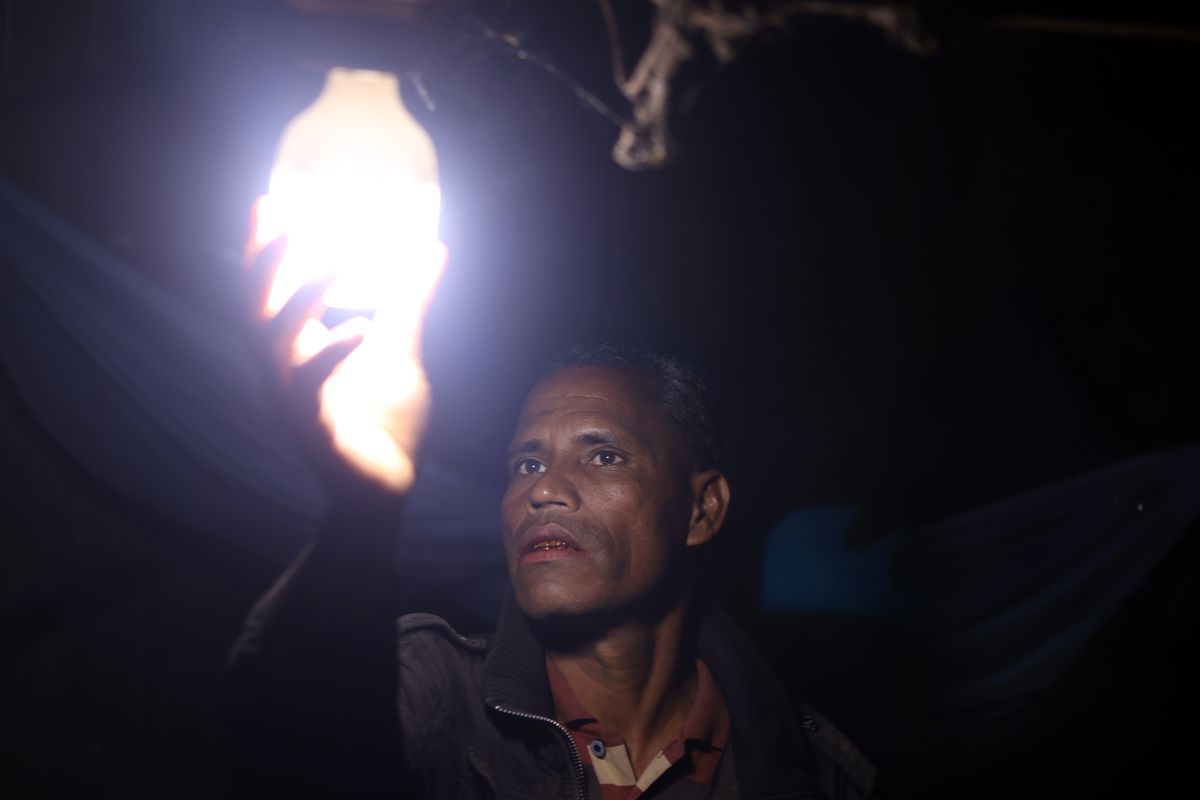 Salah satu warga Desa Mata Redi, Sumba Tengah, Nusa Tenggara Timur (NTT) memasang lampu di rumahnya, Jumat (9/5/2025). Desa Mata Redi mendapat hibah berupa pembangkit listrik tenaga surya (PLTS) dari program bernama Menuju Transisi Energi Rendah Karbon Indonesia (Mentari), kerja sama antara pemerintah Inggris dan Indonesia. 