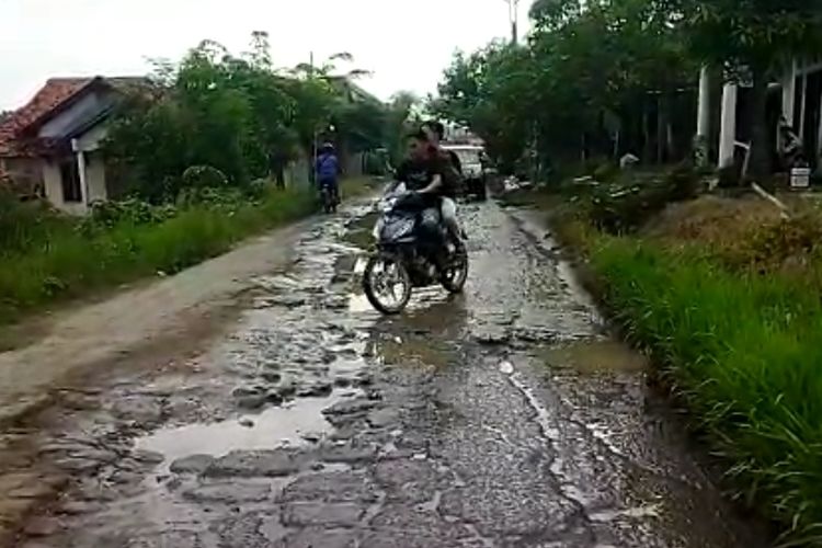 Warga melintasi jalan rusak penuh genangan di Desa Cikeusal, Kecamatan Ketanggungan, Brebes, Jawa Tengah, Rabu (1/3/2023).