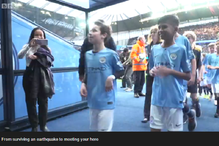 Rizky (kanan), penyintas Gempa Palu menjadi player escort pada laga Manchester City vs Leicester City, Senin (6/5/2019). 