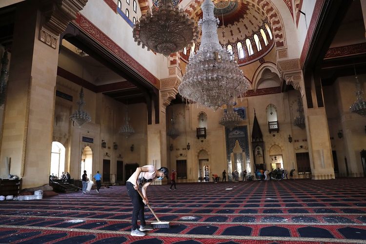 Seorang pria tampak membersihkan karpet masjid sehari setelah ledakan di Beirut, Lebanon. 
