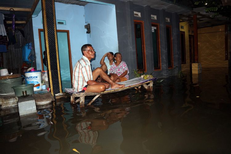 Warsi (kanan) bersama kerabatnya duduk di teras rumahnya, Minggu (5/5/2019) malam. Rumah Warsi, bersama ratusan rumah lainnya di Dusun Beluk Desa Jombok Kecamatan Kesamben Kabupaten Jombang, sejak Rabu (1/5/2019) lalu dikepung banjir.                      