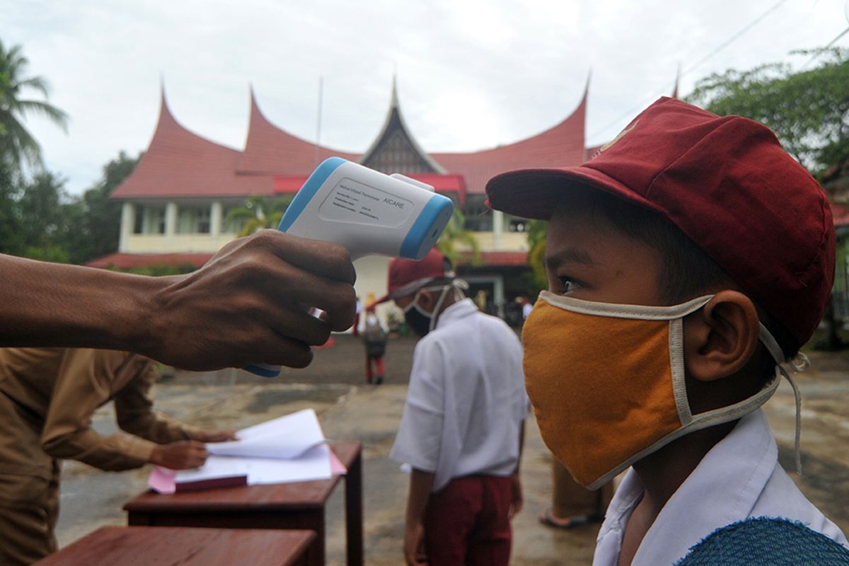 Guru memeriksa suhu tubuh murid saat hari pertana masuk sekolah di SDN 11 Marunggi, Pariaman, Sumatera Barat, Senin (13/7/2020). Kota Pariaman bersama Kabupaten Pesisir Selatan, Kota Sawahlunto dan Kabupaten Pasaman Barat merupakan empat daerah di zona hijau di Sumatera Barat yang sudah memulai aktivitas belajar-mengajar di sekolah dengan pola tatap muka langsung dan menerapkan protokol kesehatan COVID-19.