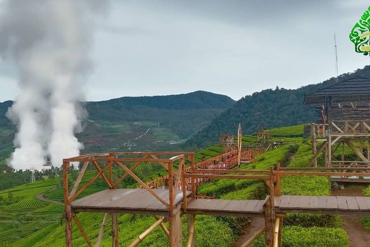 Jembatan yang melintang di tengah kebun teh  dengan pemandangan asap Kawah Wayang.