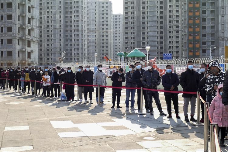 Warga dengan mengenakan masker mengantre tes Covid-19 di kota Tianjin, China utara, Minggu (9/1/2022). Tianjin menguji 14 juta warganya setelah muncul belasan kasus Covid-19 yang dua di antaranya adalah varian Omicron.
