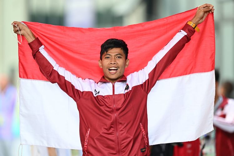 Atlet para-atletik Indonesia, Saptoyogo Purnomo, membentangkan bendera Merah Putih setelah meraih medali emas Asian Games 2022 di Huanglong Sports Center Stadium, Hangzhou, China, Senin (23/10/2023). 