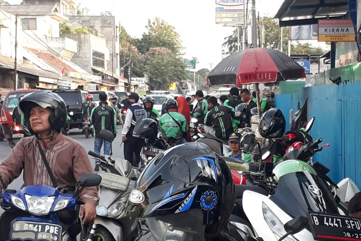 Tampak pengemudi Ojek Online di Jalan Raya Perjuangan dekat Stasiun Bekasi berjajar memarkirkan kendaraannya di badan Trotoar, Minggu (16/9/2018).