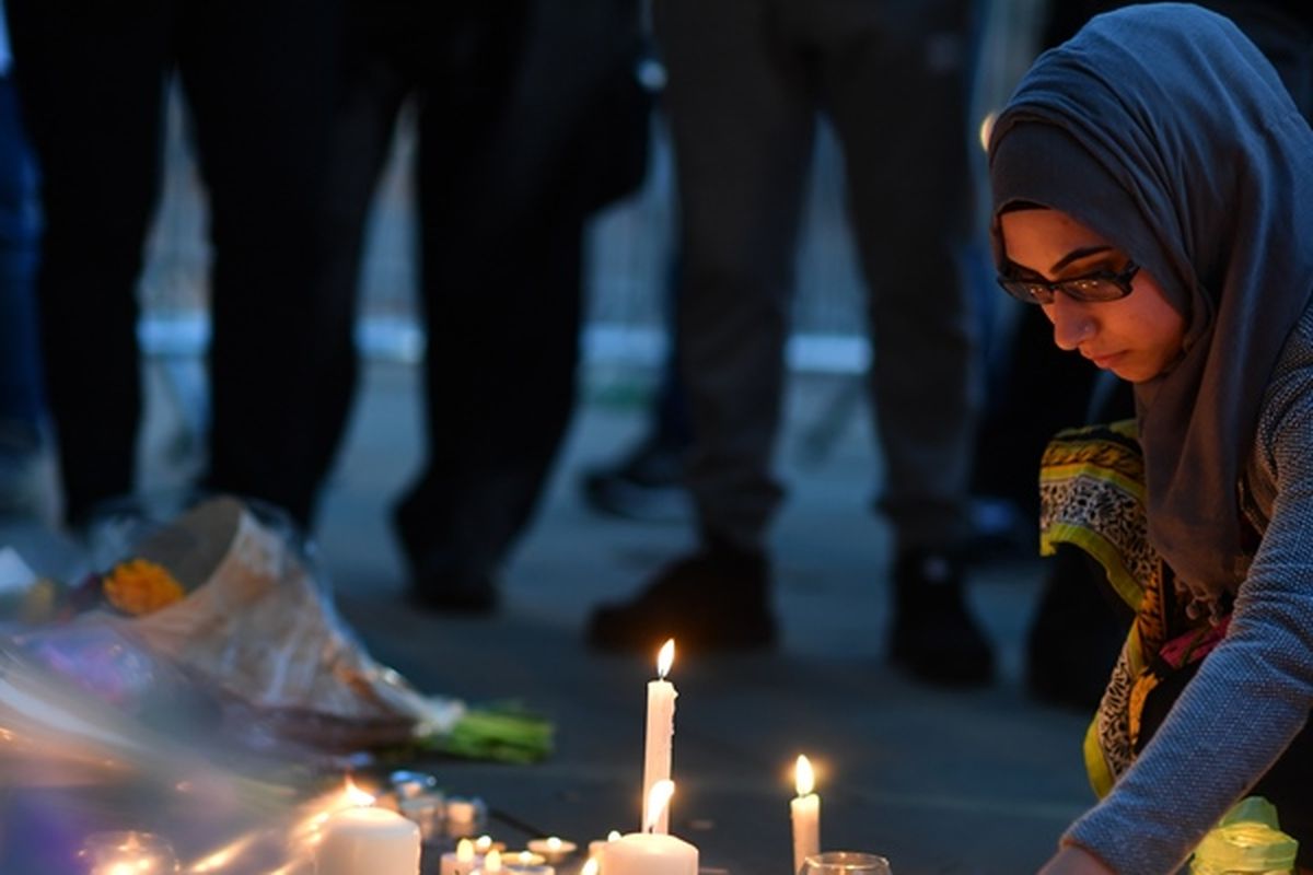 Seorang perempuan menyalakan lilin di Albert Square, Manchester, Selasa (23/5/2017) malam, dalam doa bersama untuk mengenang 22 korban tewas akibat serangan teror di kota itu.