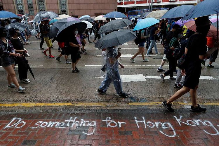 Pengunjuk rasa memakai masker membawa payung berjalan saat reli anti-pemerintah di Causeway Bay, Hong Kong, China, Minggu (6/10/2019). Ribuan demonstran bermasker turun ke jalan buntut larangan penggunaan masker wajah yang diterapkan pemerintah setempat.