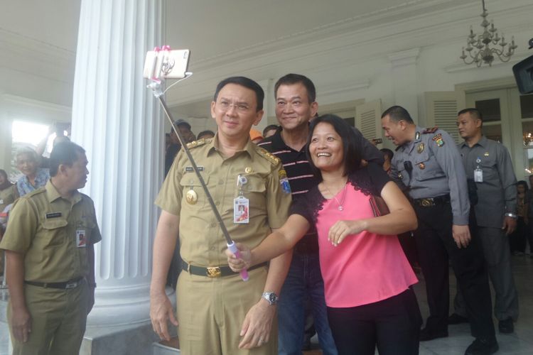 Gubernur DKI Jakarta Basuki Tjahaja Purnama melayani permintaan foto warga pada hari pertamanya aktif di Balai Kota, Senin (17/4/2017). 
