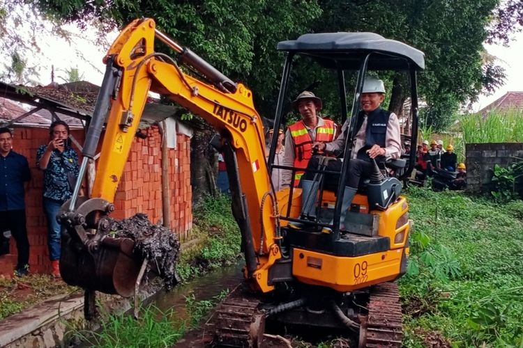 Pj Wali Kota Malang, Wahyu Hidayat turun langsung menggunakan excavator mini untuk mengangkat sedimen saluran irigasi yang berada di Jalan Raya Arjowinangun, Kecamatan Kedungkandang pada Kamis (4/7/2024). 