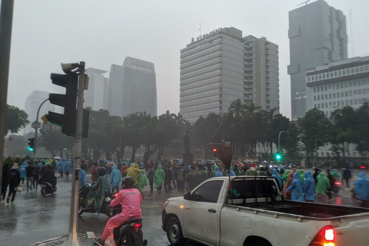 Massa aksi menolak Undang-Undang Cipta Kerja berlarian membubarkan diri ke arah Jalan Medan Merdeka Selatan setelah hujan lebat mengguyur lokasi aksi di Patung Kuda Jakarta Pusat, Jumat (16/10/2020), Jumat (1