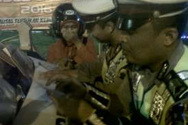 Anggota Satlantas Polres Demak, menulis surat tilang untuk  Siti (25), warga Sampangan, Kecamatan Demak Kota, yang sempat memarahi petugas saat terjaring rasia kendaraan di depan Pendopo Demak , Rabu (25/5/2016)