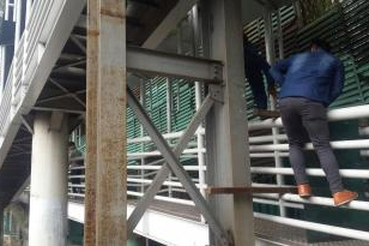 Pejalan kaki nekat panjat pagar kembatan penyebrangan orang (JPO) Halte Transjakarta Polda Metro, Jalan Jenderal Sudirman, Jakarta Pusat, Selasa (17/11/2015).