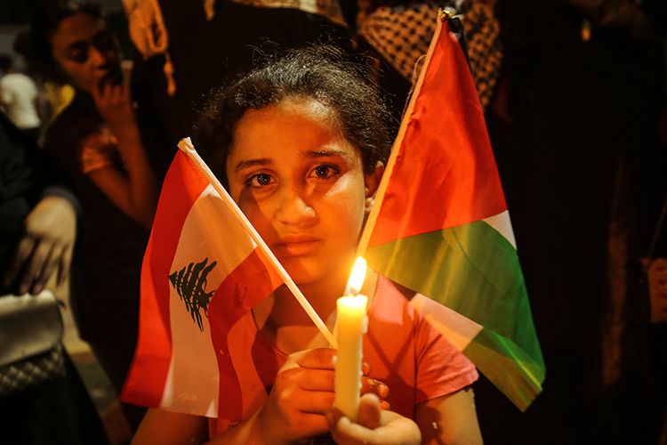 Seorang gadis Palestina membawa bendera nasional negaranya dan bendera Lebanon di Rafah, Jalur Gaza Selatan, Palestina, saat acara solidaritas atas insiden ledakan di Lebanon, Rabu (5/8/2020). Ungkapan duka dan solidaritas mengalir dari berbagai penjuru dunia atas insiden ledakan dahsyat di Beirut, Lebanon, Selasa (4/8/2020), yang menewaskan lebih dari seratus orang.