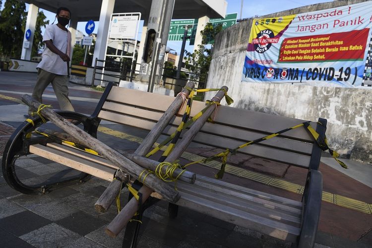 Seorang warga melintasi bangku trotoar yang disegel di Rawamangun, Jakarta, Selasa (5/5/2020). Penyegelan sementara bangku trotoar tersebut untuk mencegah kerumunan warga sebagai upaya memutus rantai penyebaran COVID-19. ANTARA FOTO/Wahyu Putro A/hp.