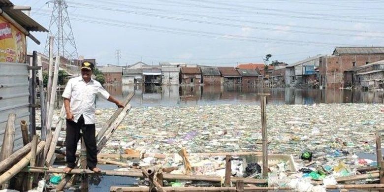 Potret Ketua RW 13, Edy Suwarno, dengan latar belakangan tumpukan sampah di bekas tambak di Tambakrejo, Kota Semarang, Jawa Tengah.