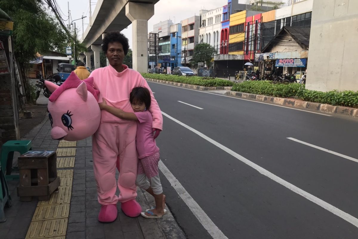 Warkuatno (41) bersama anak sulungnya, Bunga (9) berjalan kaki di pinggir Jalan Raya Fatmawati, Cilandak, Jakarta Selatan. Warkuatno menjadi badut keliling untuk menafkahi keluarganya.