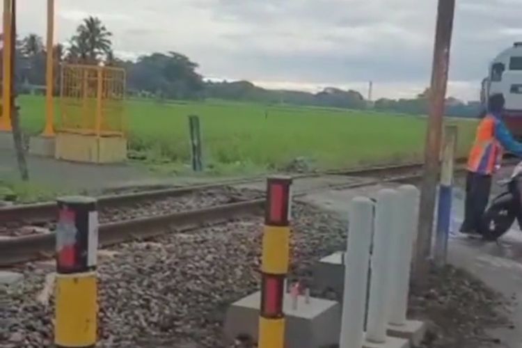 Tangkapan layar dari video viral yang menunjukkan petugas perlintasan rel kereta api di Kabupaten Malamg menghentikan pengendara motor yang hendak lewat saat akan ada kereta melintas.