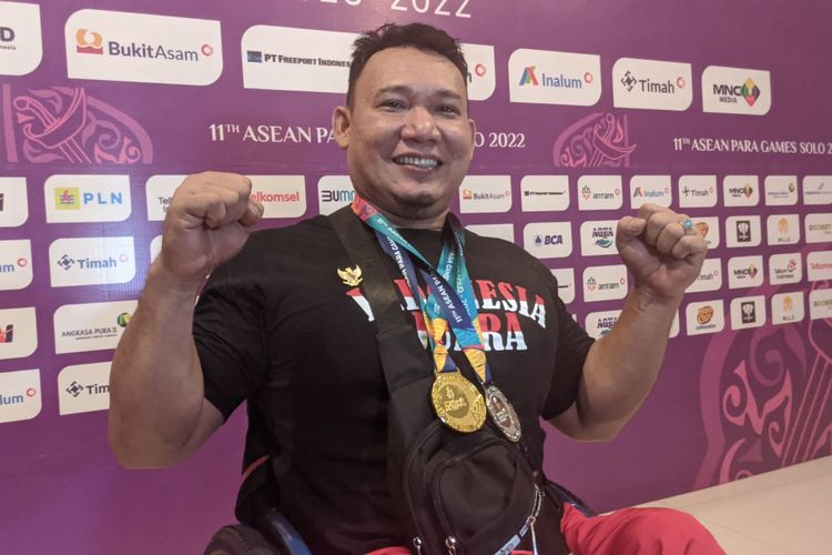 Atlet powerlifting Indonesia, Tambi Sibarani, berpose dengan medali emas ASEAN Para Games 2022 yang ia dapatkan usai menjuarai kelas 80 kg putra pada laga yang digelar di Hotel Solo Paragon, Jumat (5/8/2022).