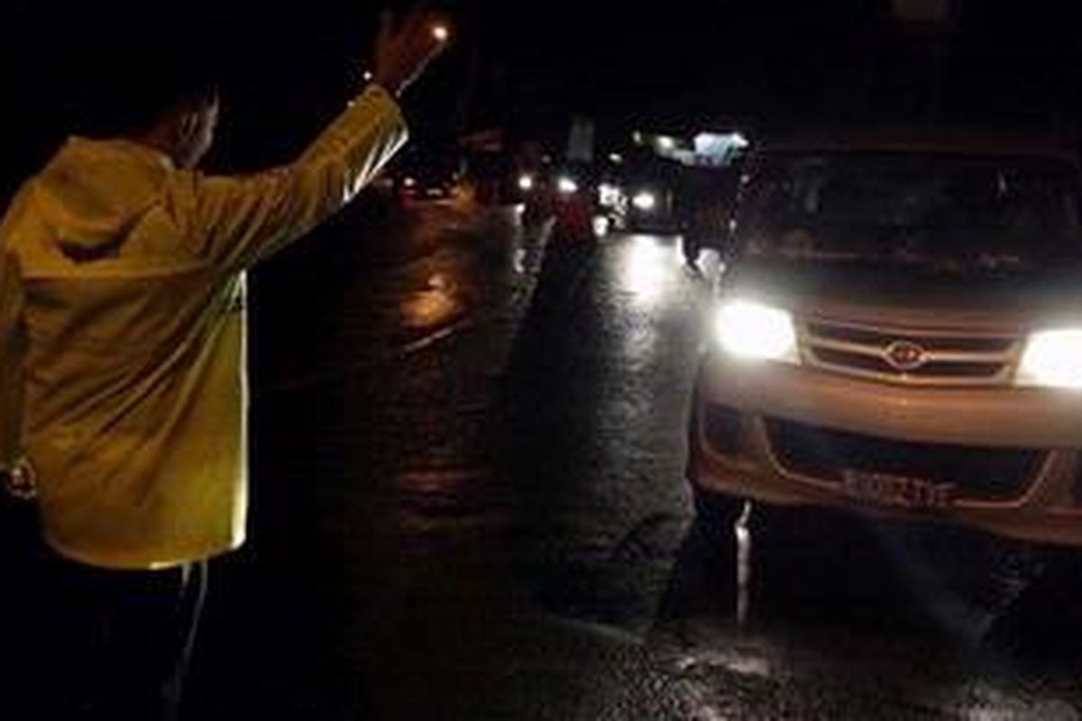 Petugas kepolisian melarang mobil untuk melintasi jalur Puncak Pass terkait longsor yang terjadi di Kampung Puncak Pass, Desa Ciloto, Kabupaten Cianjur, Jawa Barat (9/1/2013). Akibat material longsor kondisi jalan masih belum bisa dilalui oleh kendaraan bermotor. 