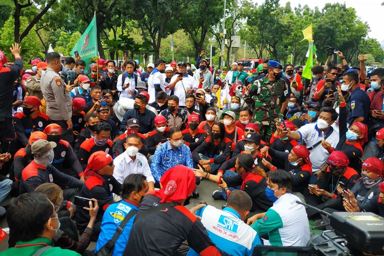 Gubernur DKI Jakarta Anies Baswedan duduk di antara massa serikat buruh yang tergabung dalam Konfederasi Serikat Pekerja Indonesia (KSPI) DKI Jakarta yang unjuk rasa di Balai Kota, Senin (29/11/2021).