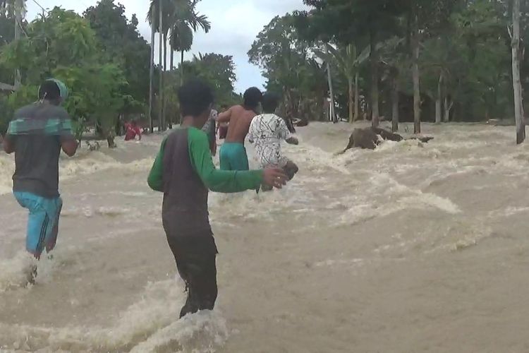 Banjir di Desa Pompengan Tengah akibat tanggul jebol membuat akses warga terputus, sejumlah warga nekat melintas untuk melakukan aktivitas, Jumat (22/05/2020).