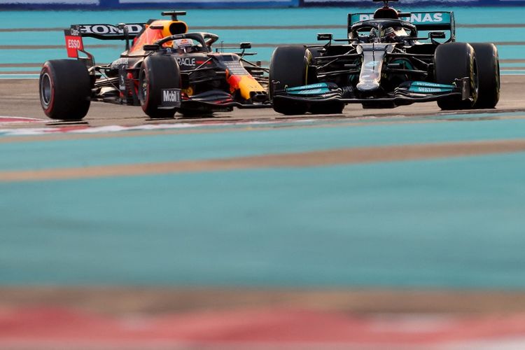 Persaingan sengit antara Lewis Hamilton dengan Max Verstappen pada lap terakhir GP Abu Dhabi 2021. (Photo by Giuseppe CACACE / AFP)