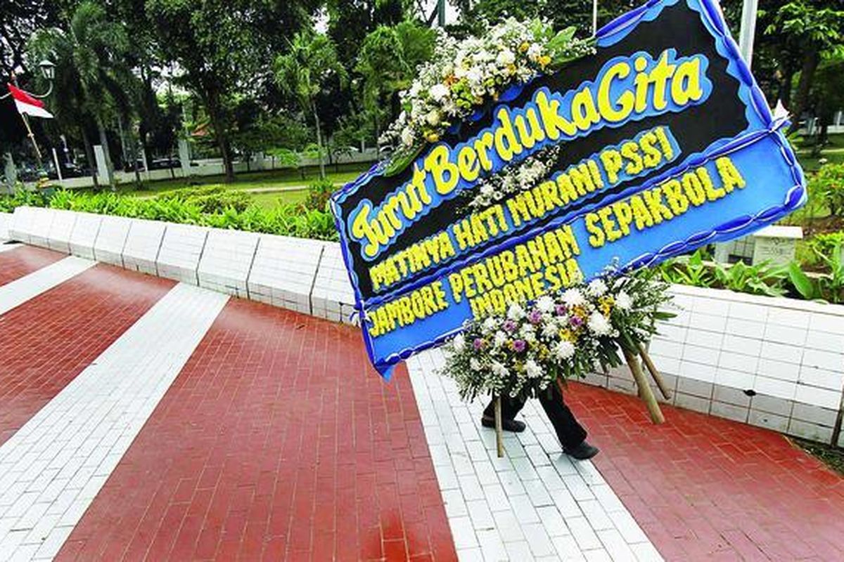 Aktivis membawa karangan bunga dukacita saat Jambore Perubahan Sepak Bola Indonesia berlangsung di Tugu Proklamasi, Jakarta, Kamis (20/1). Aliansi Suporter Indonesia dan komunitas Save Our Soccer menggelar Jambore Perubahan Sepak Bola Indonesia hingga 24 Januari, bersamaan dengan Kongres Tahunan PSSI di Bali.