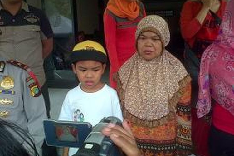 Sarjono, bocah berusia 9 tahun yang mencari ibu kandungnya dengan berjalan kaki keliling Jakarta dan ibu tirinya, Kasnia di Mapolsek Pademangan, Jakarta Utara, Sabtu (28/6/2014)