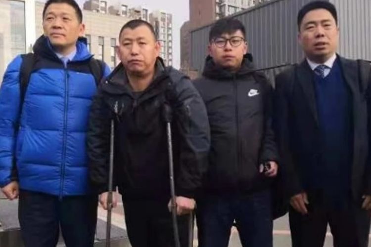 Jin Zhehong (memakai kruk) saat meninggalkan pengadilan didampingi putranya, Jin Yongxin (dua dari kanan) dan kedua pengacaranya.