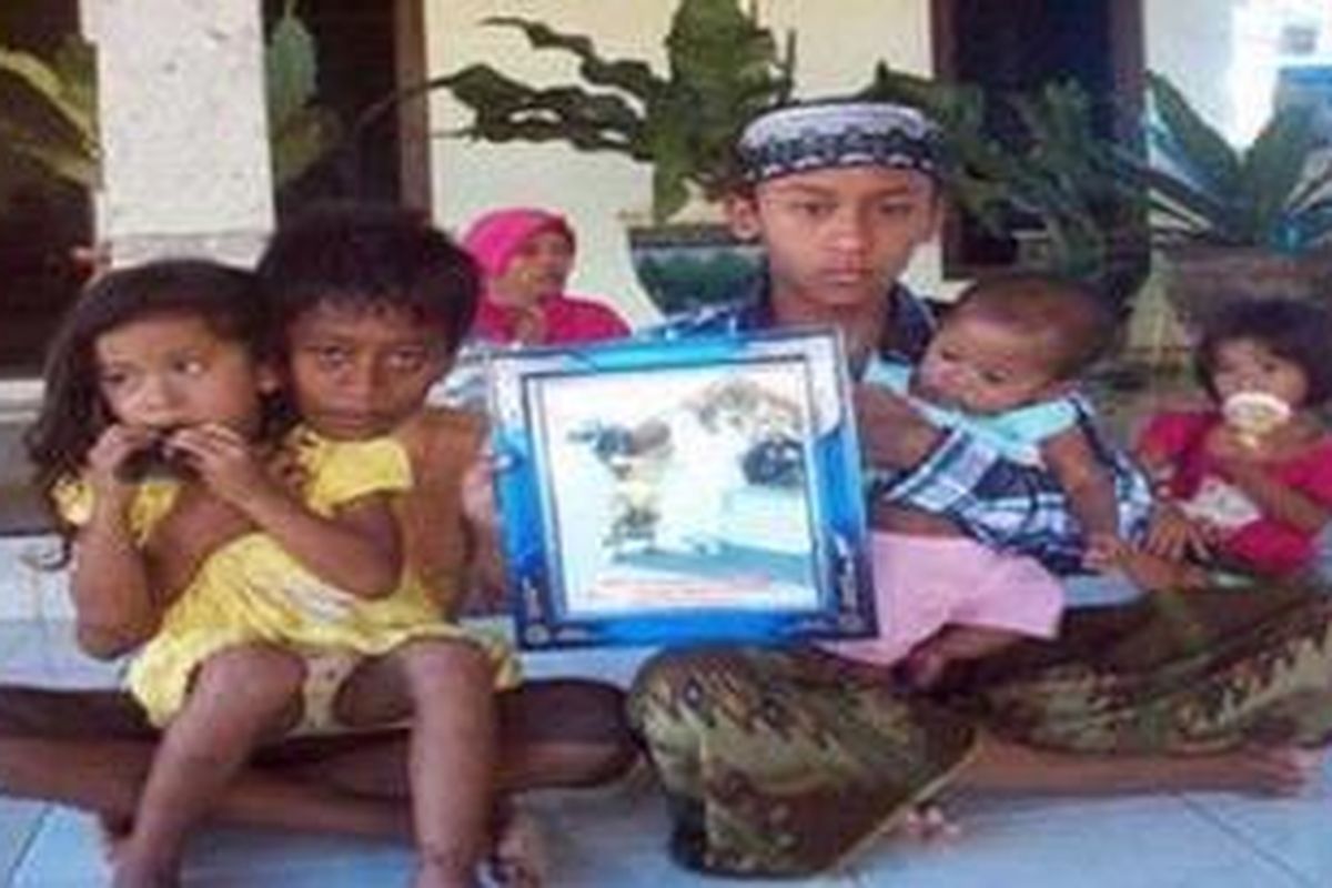 Keempat anak Bukhari dan Bai memegang foto kedua orang tuanya setelah kasus surat nikah palsu yang dititipkan ipar Bukhari.