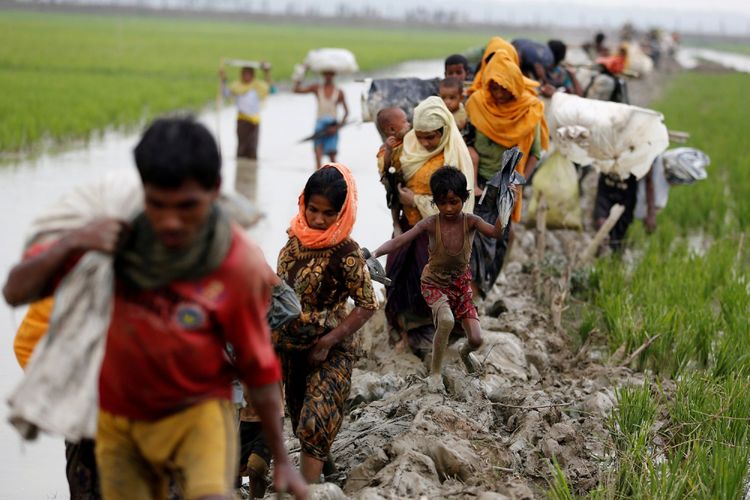 Pengungsi Rohingya berjalan di jalan berlumpur setelah menyebrangi perbatasan Bangladesh-Myanmar di Teknaf, Bangladesh, Minggu (3/9/2017). 