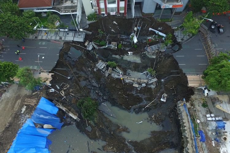 Foto aerial kondisi tanah ambles di Jalan Raya Gubeng, Surabaya, Jawa Timur, Rabu (19/12/2018). Jalan raya tersebut ambles sedalam sekitar 20 meter dengan lebar 30 meter pada Selasa (18/12/2018) malam diduga karena proyek pembangunan gedung di sekitar lokasi. ANTARA FOTO/Didik Suhartono/wsj.