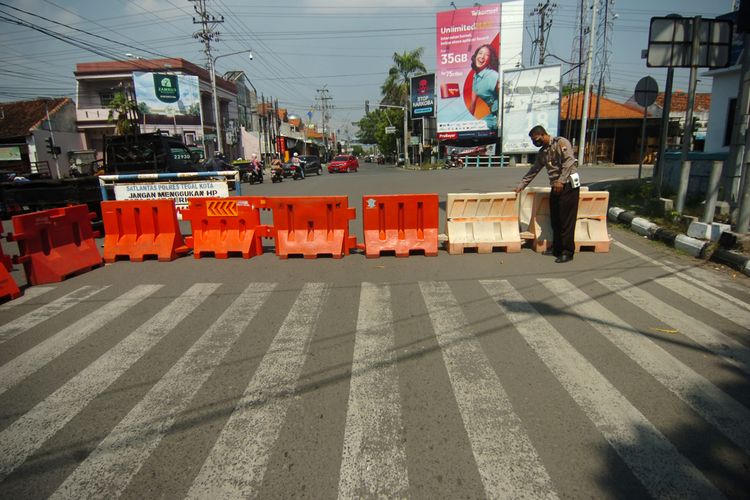 Polisi memasang barrier perempatan perbatasan jalan kota/kabupaten Tegal, Jawa Tengah, Sabtu (3/7/2021). Satlantas Polres Tegal Kota menutup dua jalan masuk ke Kota Tegal guna membatasi mobilitas warga saat pemberlakuan pembatasan kegiatan masyarakat (PPKM) Darurat di Kota Tegal yang berlangsung mulai 3 hingga 20 Juli 2021 mendatang. ANTARA FOTO/Oky Lukmansyah.