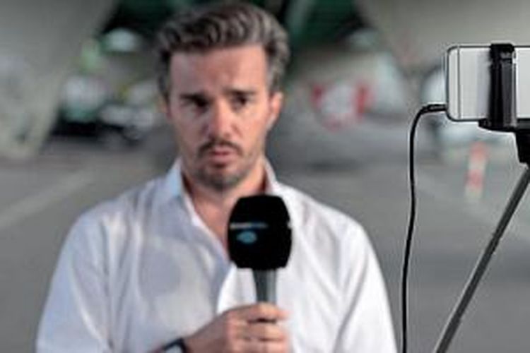 Seorang reporter stasiun TV Leman Bleu merekam siaran dengan iPhone yang terpasang di tongsis