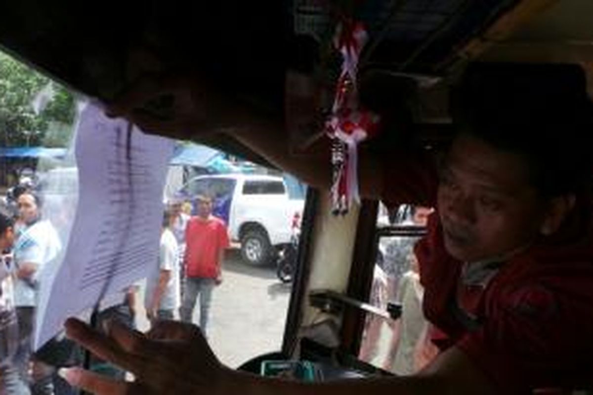 Seorang sopir Metromini membantu petugas Sudinhub Jakarta Timur menempel kertas berisi tarif baru angkutan kota di Kampung Melayu, Jumat (12/7/2013).