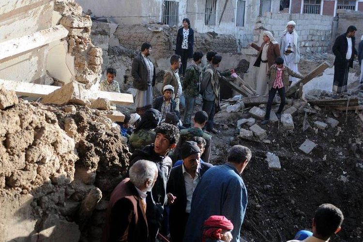 Warga sekitar memeriksa reruntuhan bangunan di kota mereka setelah serangkaian serangan udara yang dilancarkan koalisi Arab Saudi di Sanaa, Yaman.