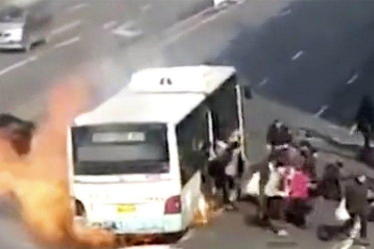 Penumpang bus berlarian keluar dari dalam bus yang terbakar di Harbin, China.