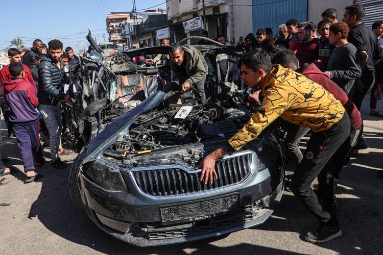 Orang-orang memeriksa mobil yang ditumpangi dua jurnalis, Mustafa Thuria, seorang juru kamera video untuk kantor berita AFP, dan Hamza Wael Dahdouh, seorang jurnalis dari jaringan televisi Al Jazeera, yang terbunuh dalam serangan yang dilaporkan dilakukan oleh Israel di Rafah, Jalur Gaza, pada tanggal 7 Januari 2024. Ayah Hamza, Wael al-Dahdouh, adalah kepala biro Al Jazeera di Jalur Gaza, dan baru-baru ini juga terluka dalam serangan tersebut. Istri dan dua anaknya terbunuh oleh serangan Israel yang terpisah pada minggu-minggu awal perang. Thuria telah bekerja dengan AFP sejak 2019. 